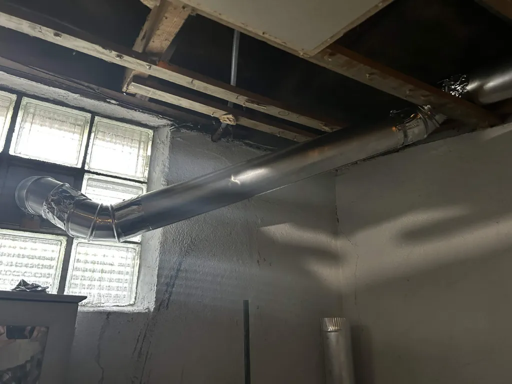Rigid metal duct run out to the basement window