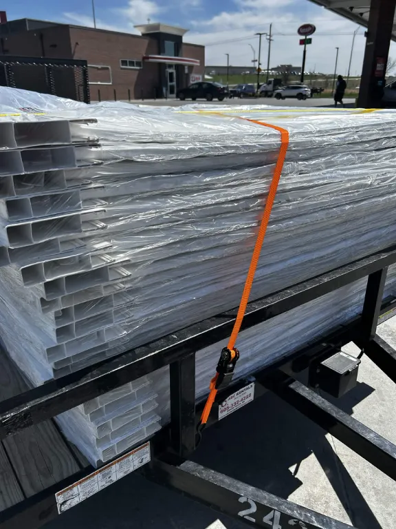 White PVC fence panels strapped to a trailer