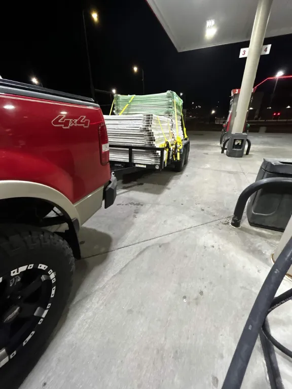 Loaded trailer of fence panels at a fuel stop at night