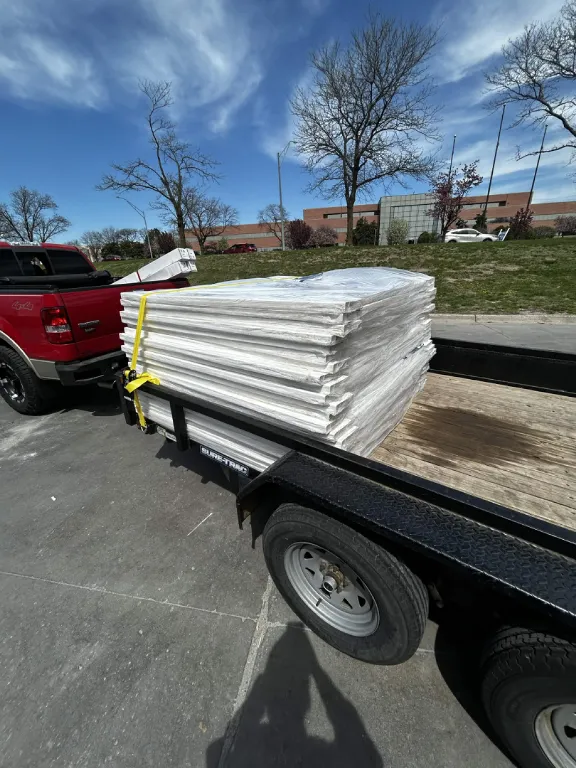 Trailer loaded with wrapped white PVC fence panels