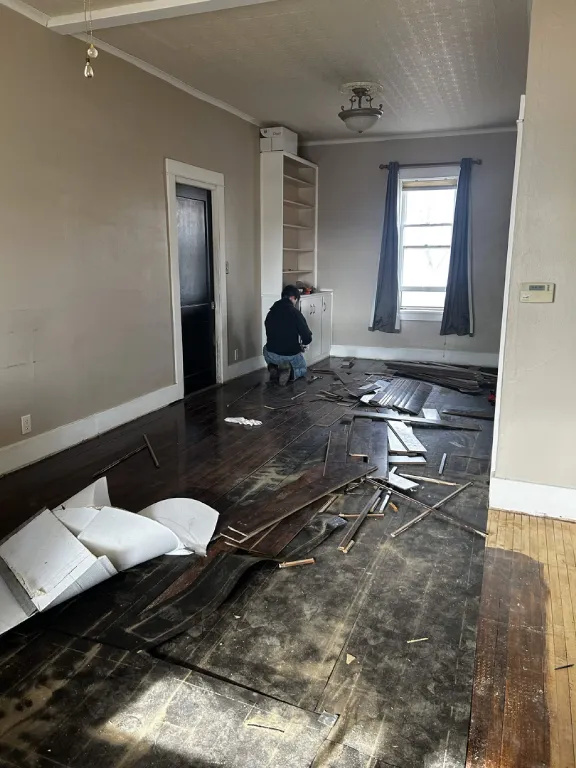 Old flooring being pulled up in an empty room