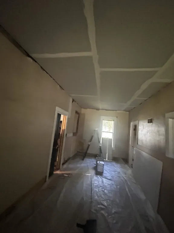 Hallway with taped ceiling seams and plastic over the floor