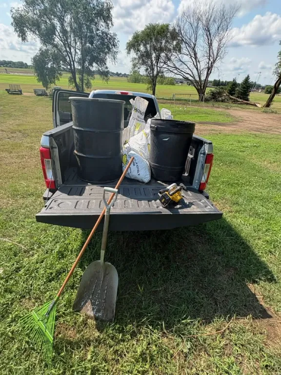 Pickup bed loaded with barrels and tools in a field