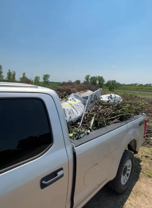 Truck bed loaded with branches and woven contractor bags at the yard waste site