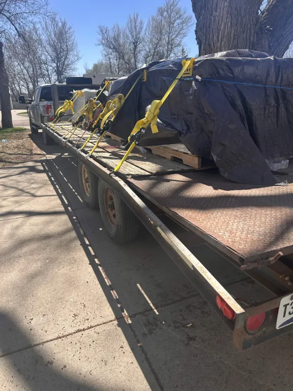 Pickup and trailer with a tarped load on a driveway