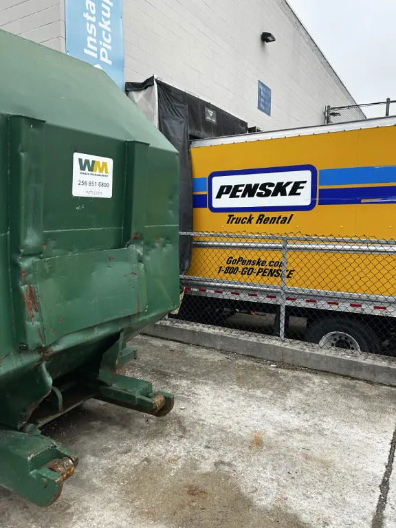 Box truck and dumpster at a dock during an overstock load out