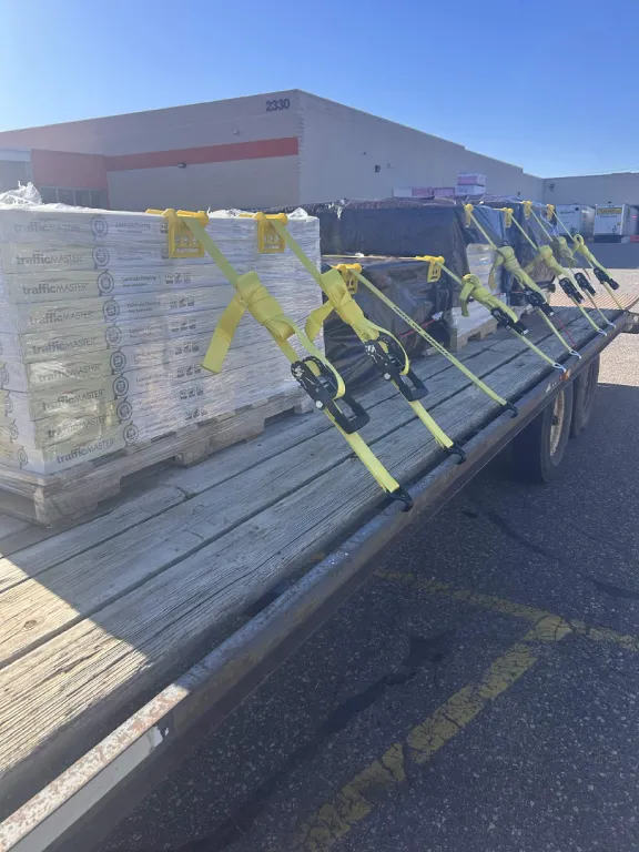 Flatbed trailer loaded with strapped pallets of flooring