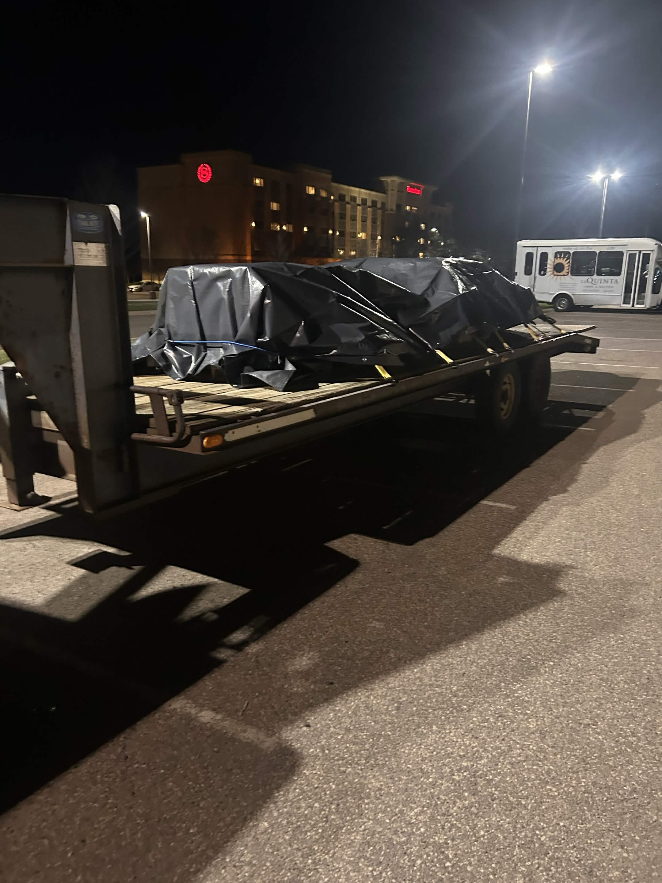 Tarped load strapped on a flatbed trailer at night