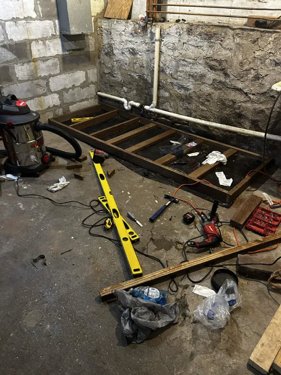 Framed wood platform and tools on a basement floor