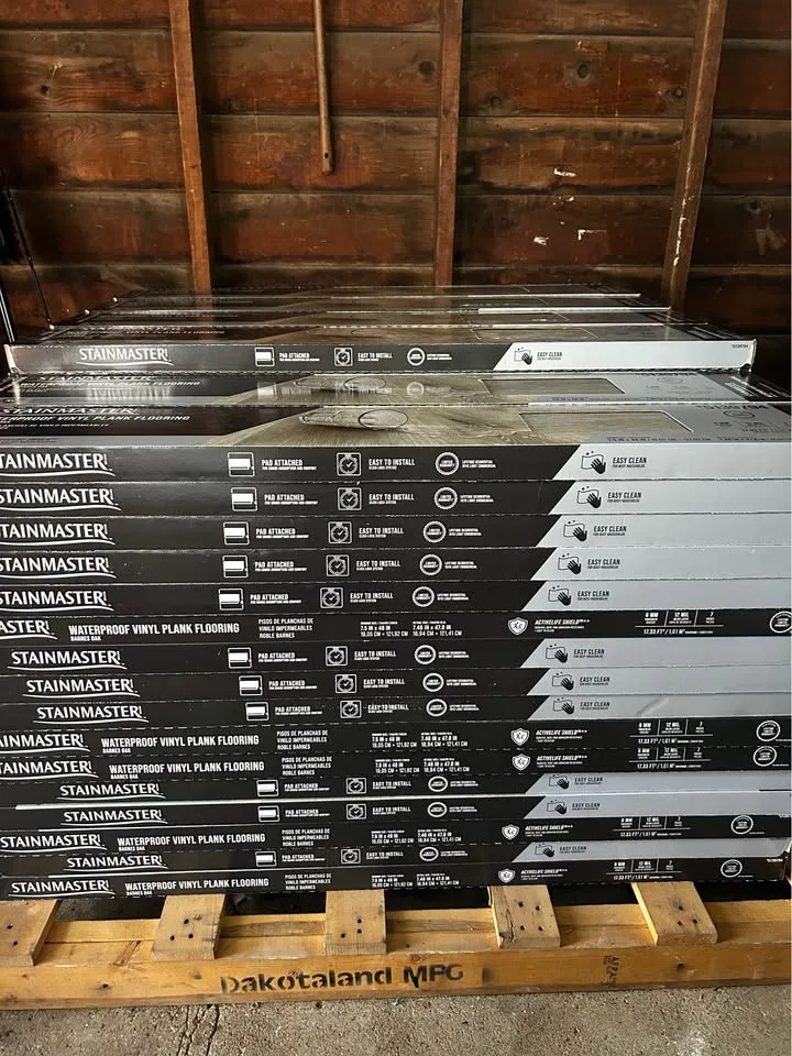 Stacked boxes of Stainmaster Barnes Oak vinyl plank flooring