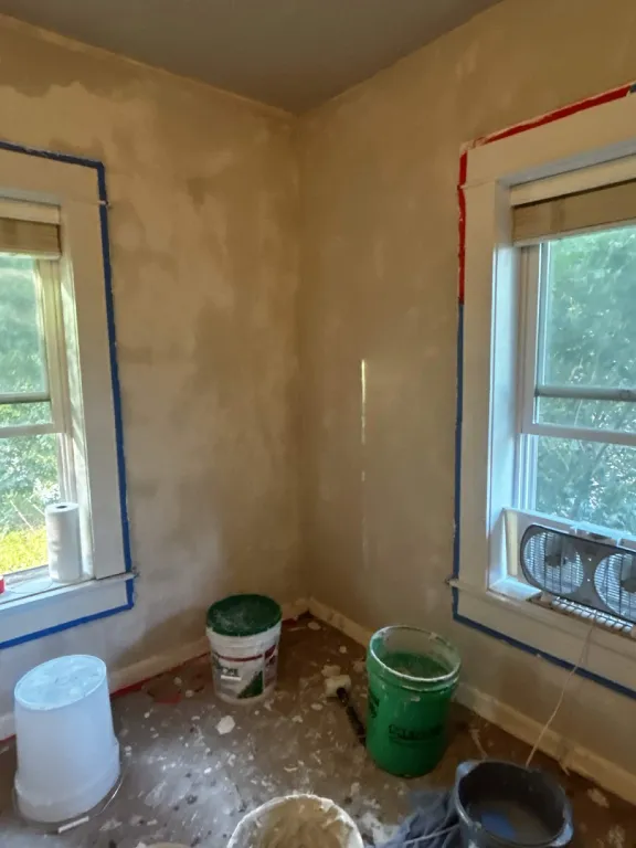 Guest room walls stripped of wallpaper and texture, patched