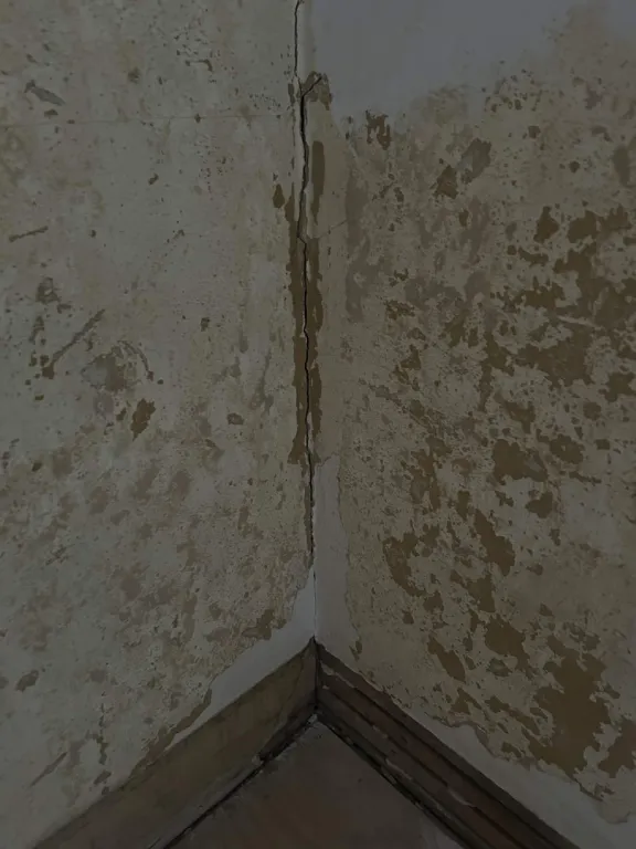Cracked and peeling plaster wall corner